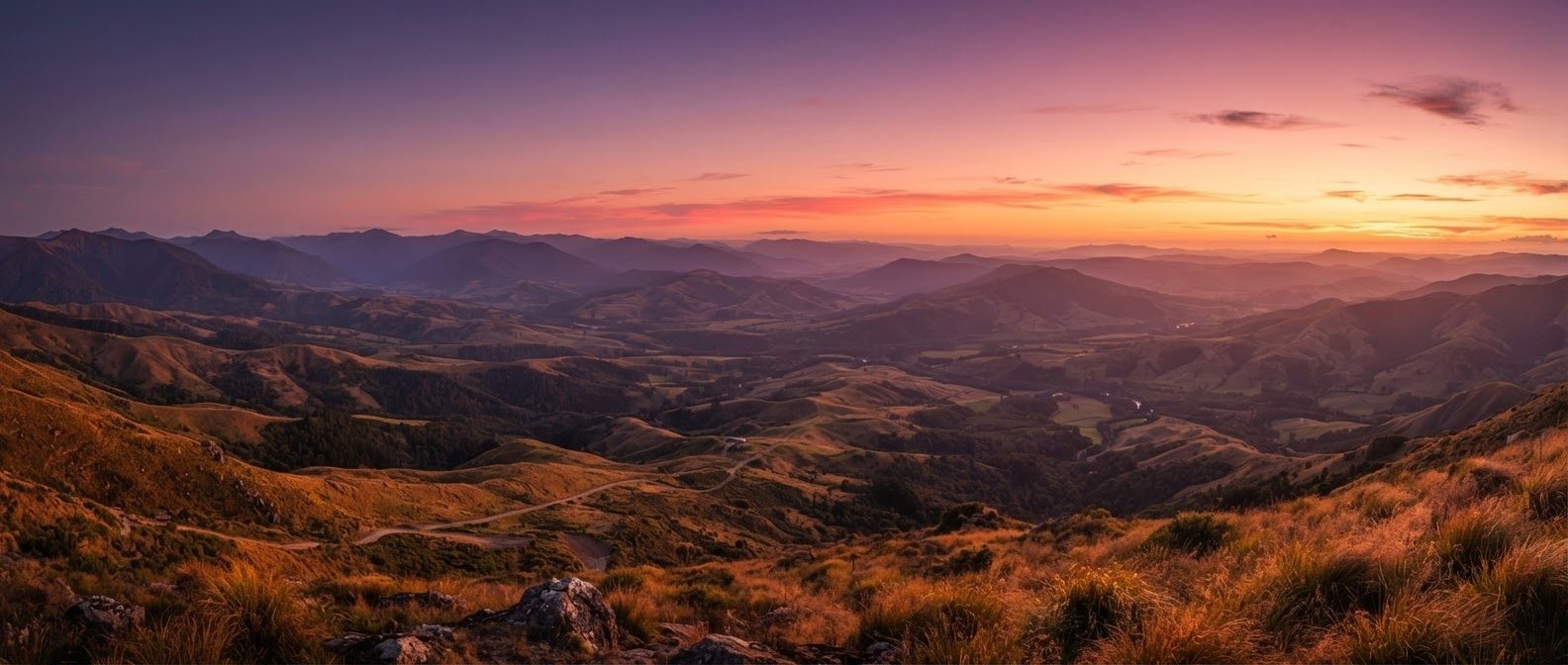 Rolling green hills and valleys under a wide sunset sky